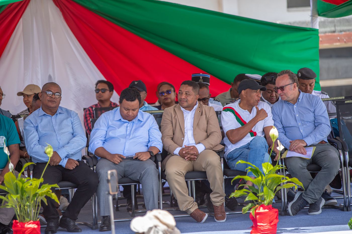 Government ministers and dignitaries seated at the close of a project event in Fort Dauphin, beneath the Malagasy flag